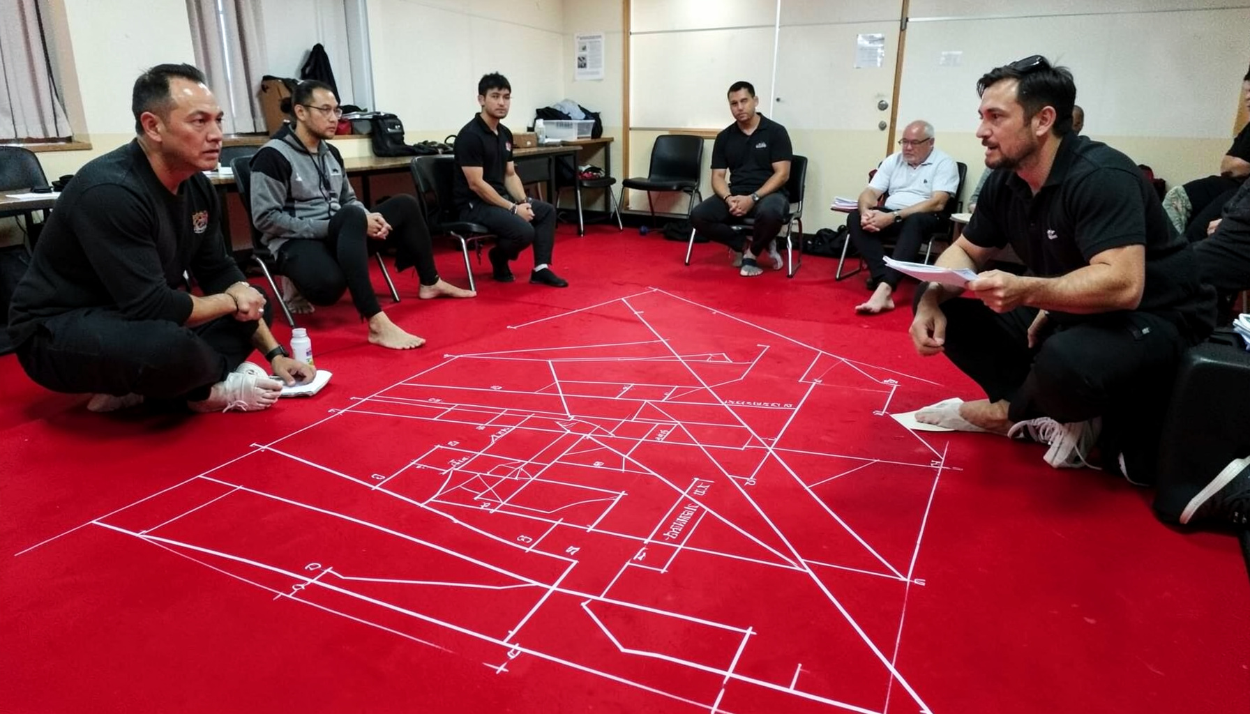 Muay Thai trainers in a seminar room setting, professional and instructional atmosphere